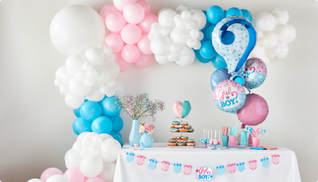 A pink, white and blue balloon arch and balloon bouquet surround a small, decorated snack table.