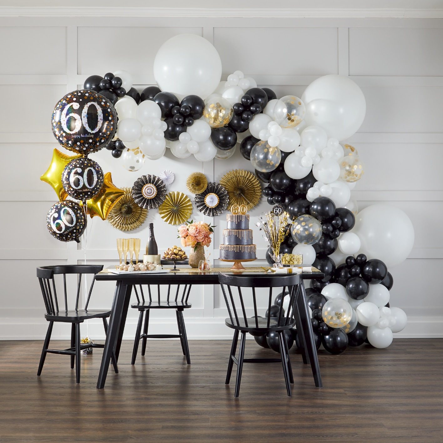 Black, white & gold balloon arch behind an elegant birthday table setting atop a black dining table. 