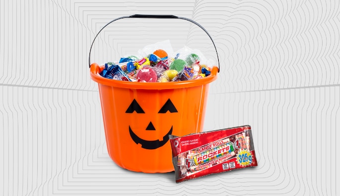 Jack-o-lantern shaped treat bucket filled with candy and a package of Rocket candy.