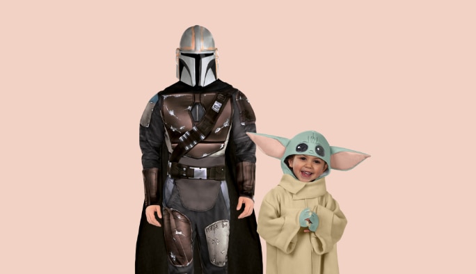 Adult wearing a Mandalorian costume with a toddler wearing a Baby Yoda costume.