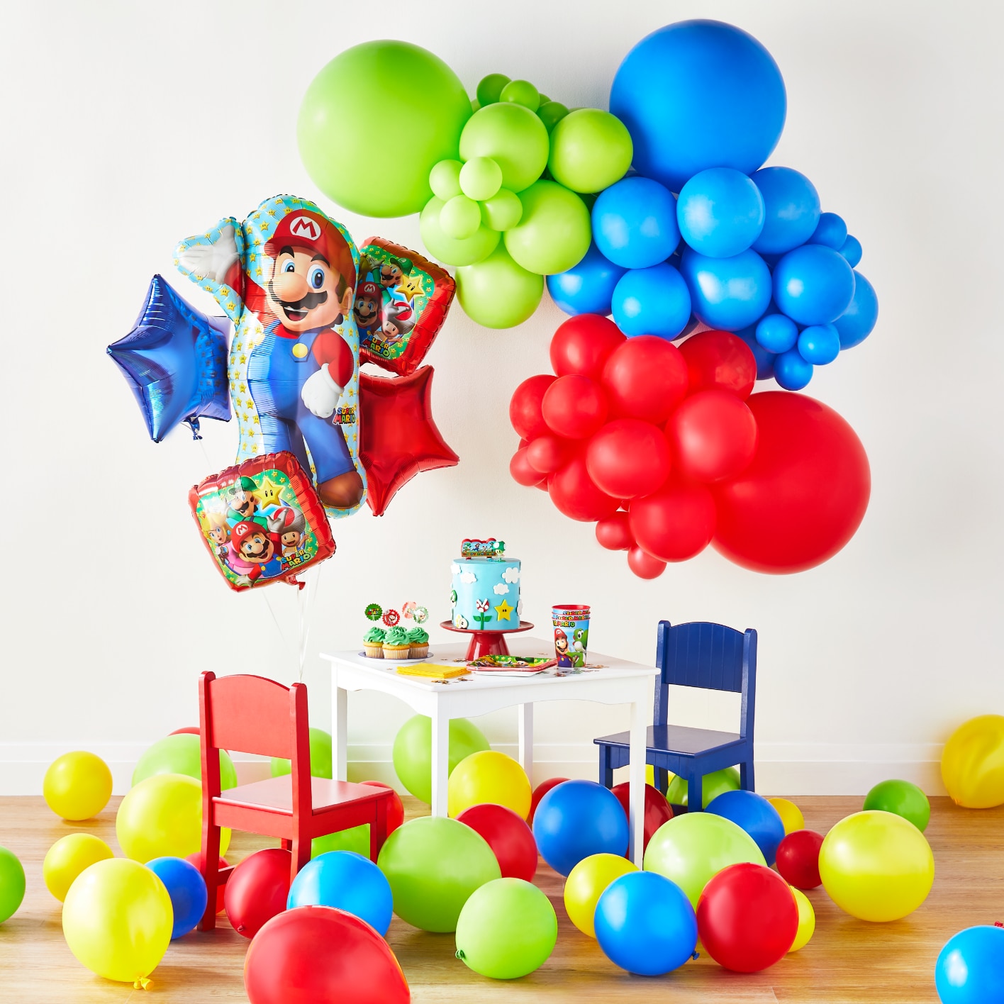 Ballons Super Mario bleus, verts et jaunes avec des décorations de fête sur une table blanche pour enfants