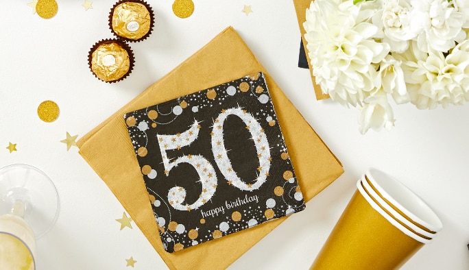 Serviettes de table dorées, blanches et noires pour 50e anniversaire, fleurs blanches et décorations.