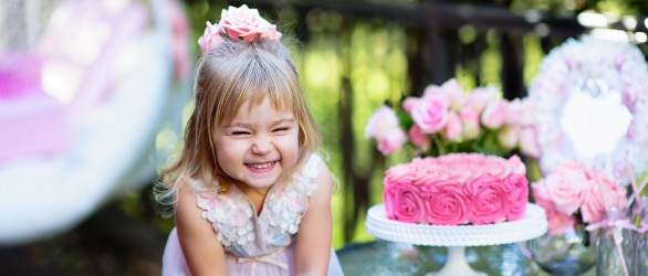 Une fillette à l’extérieur entourée de ballons et d’un gâteau d’anniversaire rose