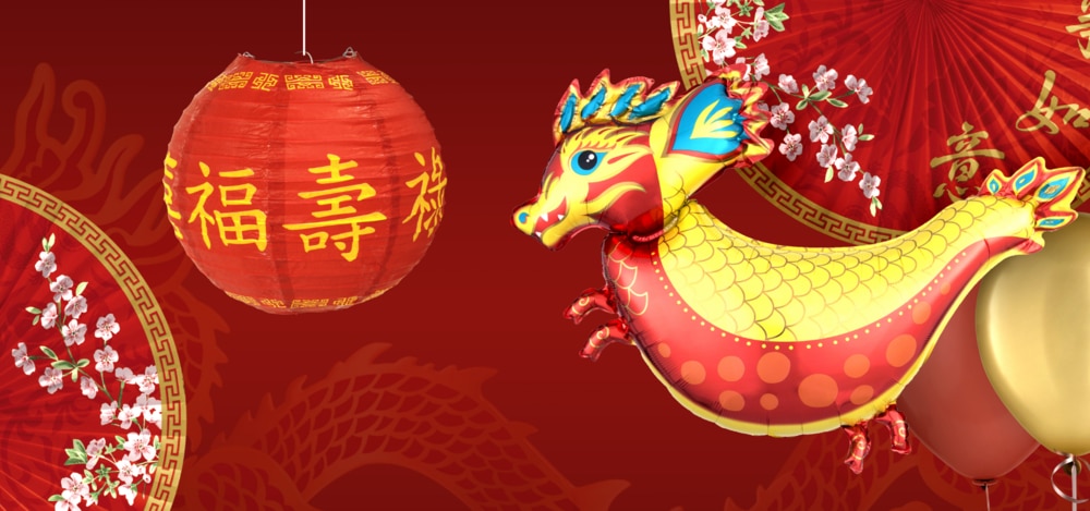 A variety of gold and red décor including a foil Lunar New Year dragon balloon and a round paper lantern against a red background.