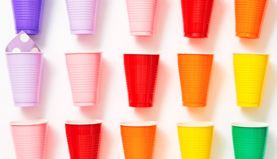 An assortment of coloured plastic party cups arranged in the style of a grid against a white background.  