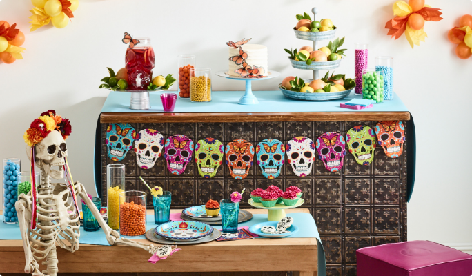 A room styled with a multicoloured sugar skull garland, a prop skeleton, floral décor, and colourful accessories.