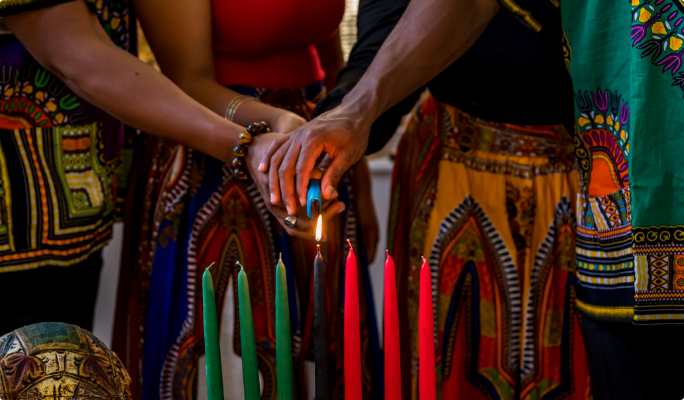 Un groupe de personnes allumant le Kinara de la Kwanzaa.