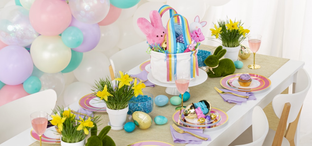 A table styled with pastel coloured dinnerware and décor, including Easter moss laying bunnies and decorative eggs.