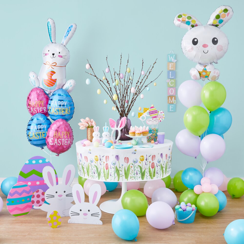 Une pièce remplie de ballons et décorations, y compris des piquets à lapins et œufs de Pâques et une nappe à tulipes. 