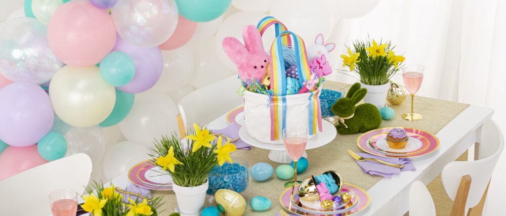 A table styled with pastel coloured dinnerware and décor, including Easter moss laying bunnies and decorative eggs.
