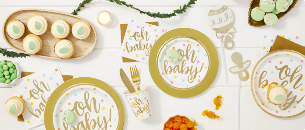 A variety of “Oh Baby” paper plates, cups and napkins, desserts and baby shower decorations on a table. 