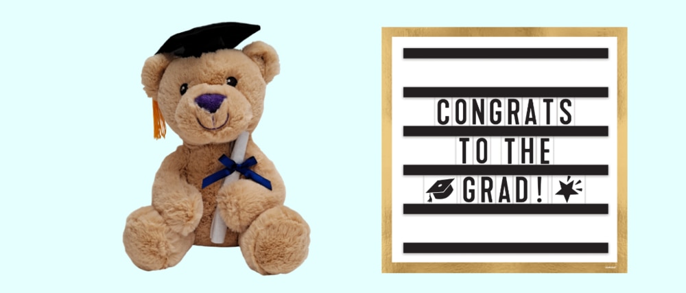 A light brown plush graduation bear toy and a gold, white and black Graduation Message Board Sign.