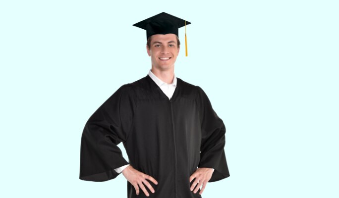 A young man wearing a standard black adult graduation gown and graduation cap with a tassel. 