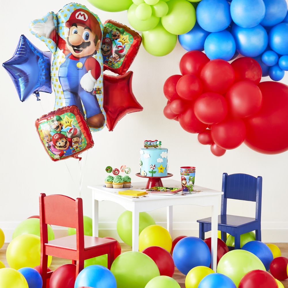 An assortment of gold, white and multicoloured party supplies on a tabletop including Confetti Fun Cake Time napkins.