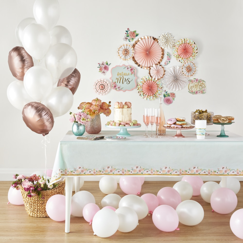 Une table à desserts avec une nappe menthe florale et plusieurs ballons et décorations vert menthe, or rose et blancs.