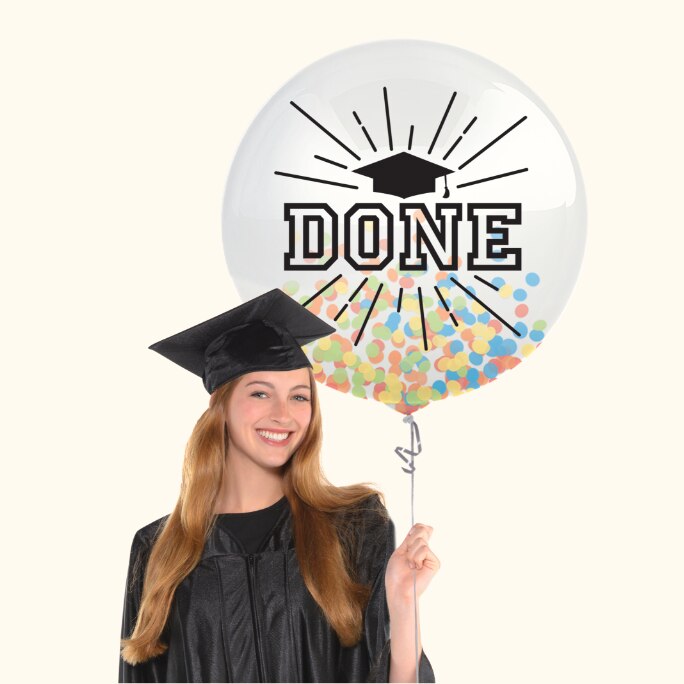 A woman dressed in a graduation cap and gown holding a helium filled multicoloured graduation confetti balloon.