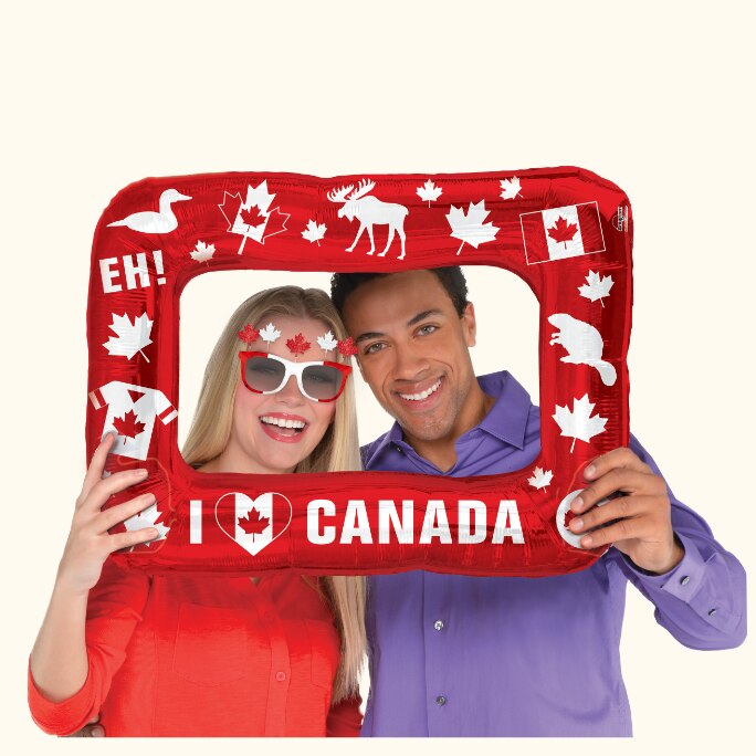 A couple posing with a Canada Day inflatable frame.