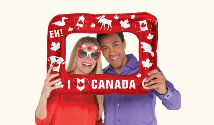 A couple posing with a Canada Day inflatable frame.