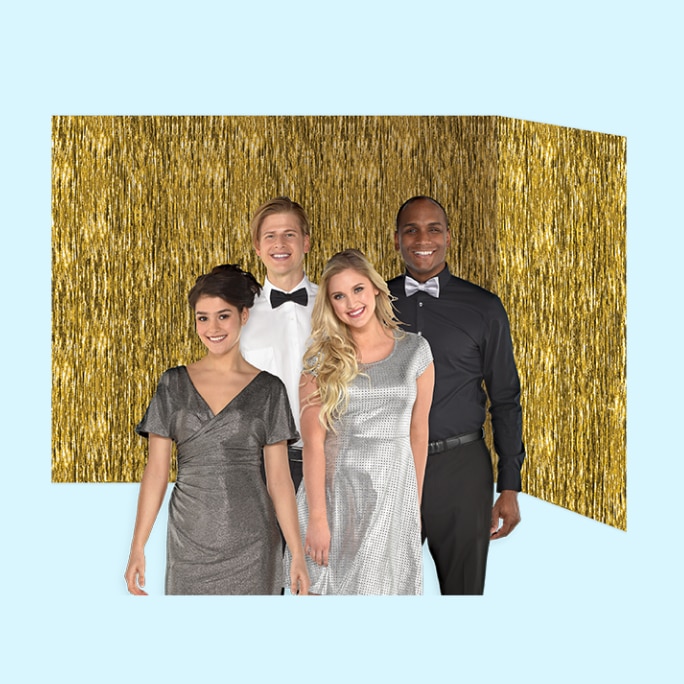 Four adults dressed in cocktail attire posing in front of a metallic gold room roll backdrop hung on a wall. 