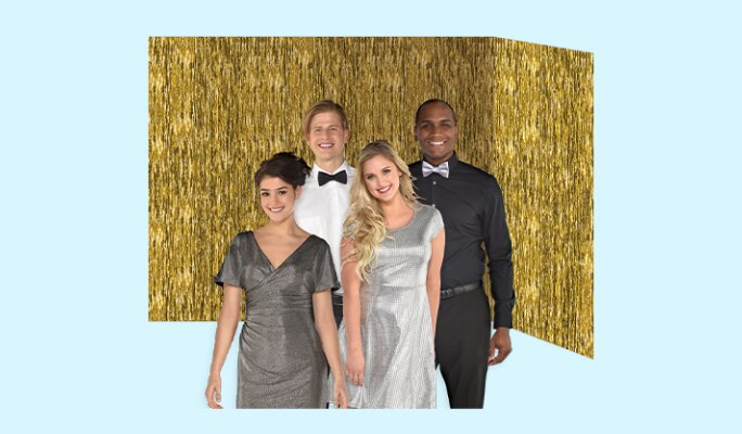 Four adults dressed in cocktail attire posing in front of a metallic gold room roll backdrop hung on a wall. 