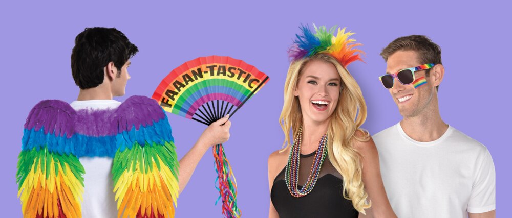 Three adults wearing Pride-themed accessories including rainbow feather wings, a feather headband and rainbow handheld fan.
