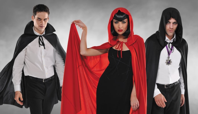Two men wearing black vampire capes and a woman wearing a red hooded cape. 
