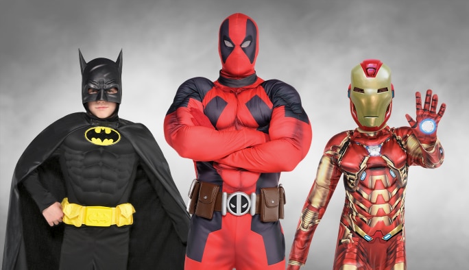 Un enfant portant un costume Batman, un adulte portant un costume Deadpool et un enfant portant un costume Iron Man.