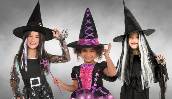 Three girls wearing witch costumes, wigs and assorted witch accessories. 