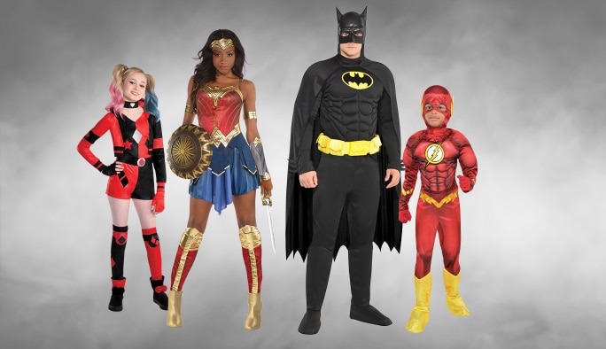 Deux adultes et deux enfants portant des costumes de superhéros DC Comics.
