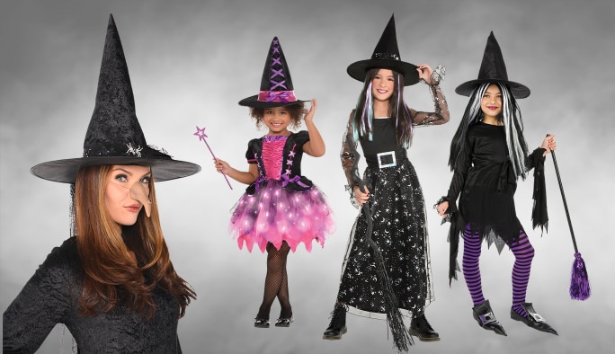 Une femme et trois fille portant des costumes, perruques et accessoires de sorcières.