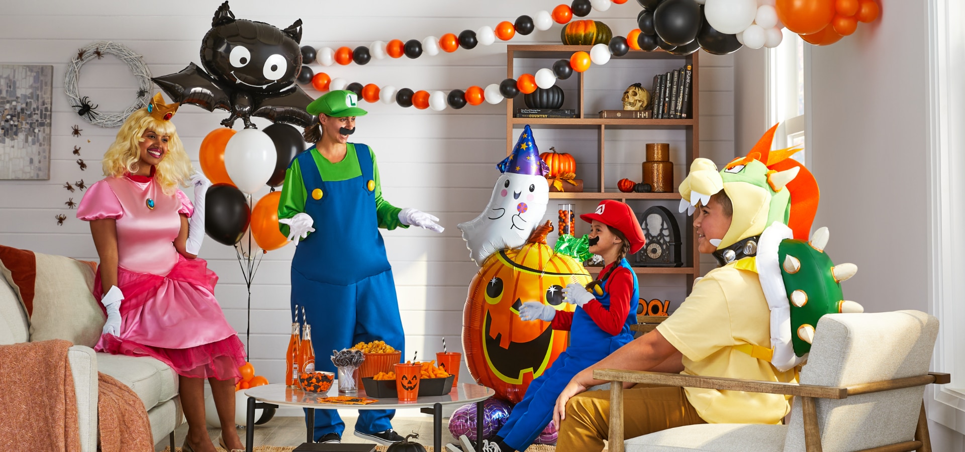 A family wearing Super Mario character costumes in a living room filled with Halloween balloons and decorations.