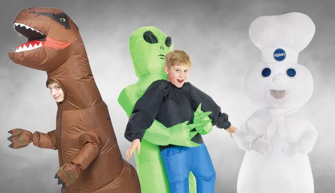 Un enfant portant un costume de tyrannosaure, un enfant portant un costume d’extra-terrestre qui soulève un adulte et un adulte portant un costume du Bonhomme Pilsbury.