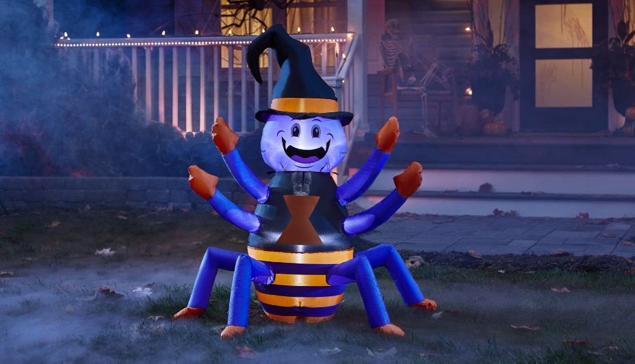 A purple, black and orange 6-ft happy spider inflatable decoration on a front lawn.