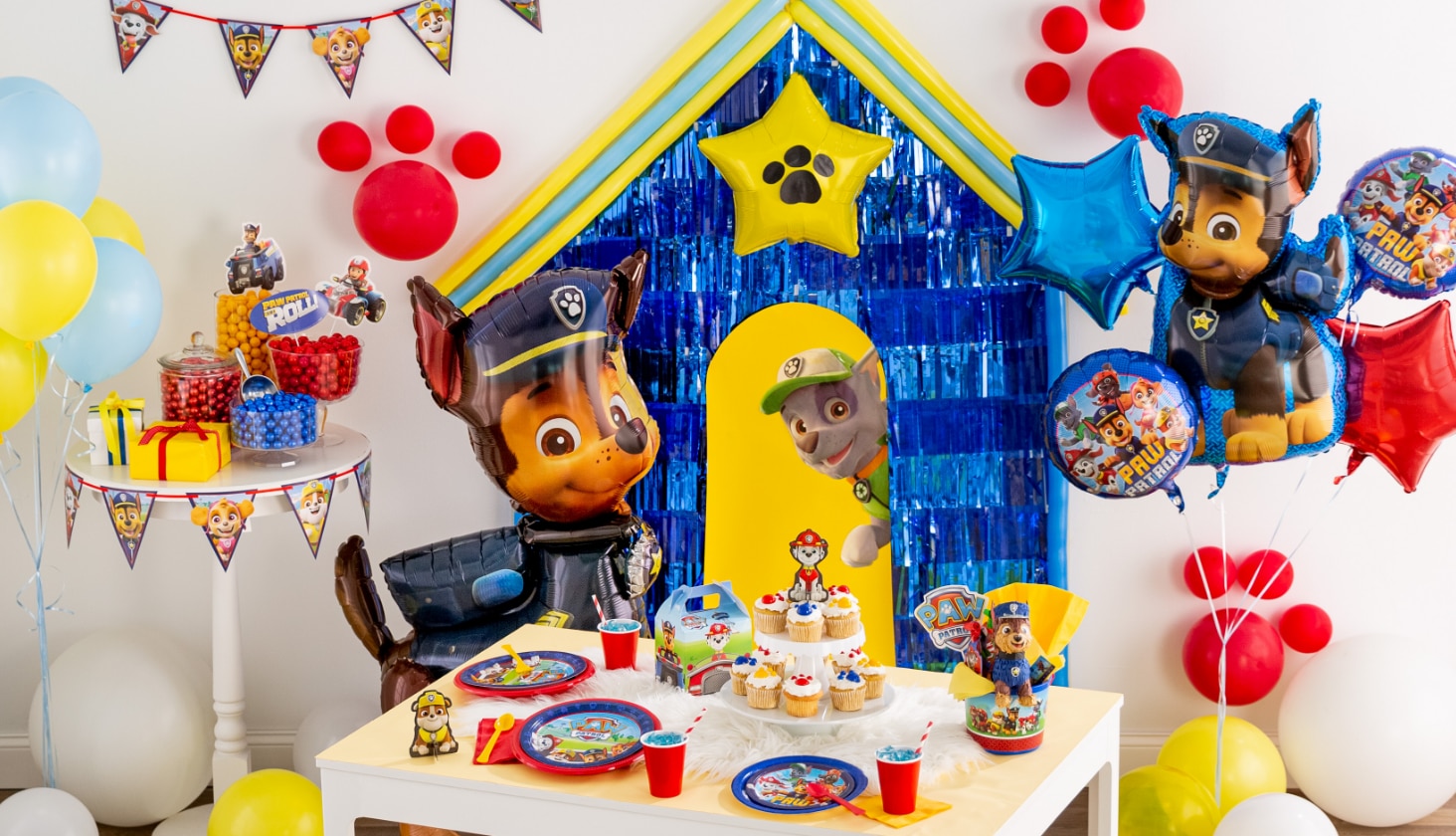 A room decorated with a PAW Patrol balloon bouquet and assorted PAW Patrol party supplies.