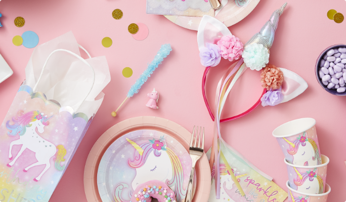 An Enchanted Unicorn deluxe headband on a table with candy and themed party supplies.