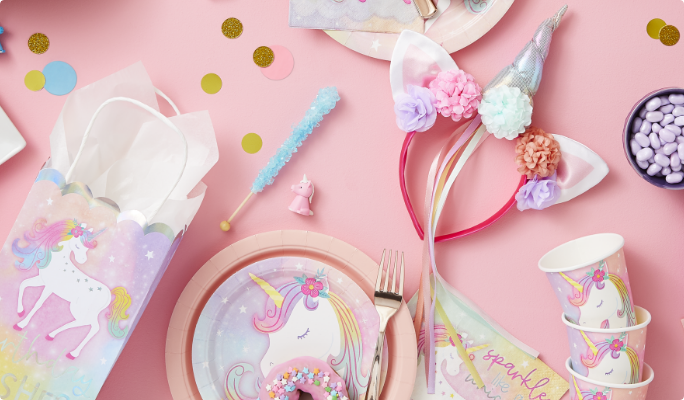 Un serre-tête de luxe Licorne enchantée sur une table avec des bonbons et des articles de fête thématiques.