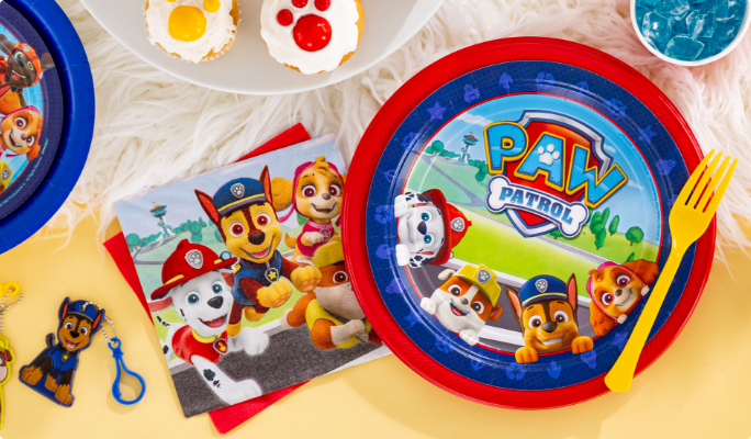 A PAW Patrol Adventures paper plate and matching party supplies on a table.