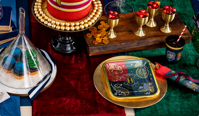 A Harry Potter Square paper plate, desserts and gold accessories on a table. 