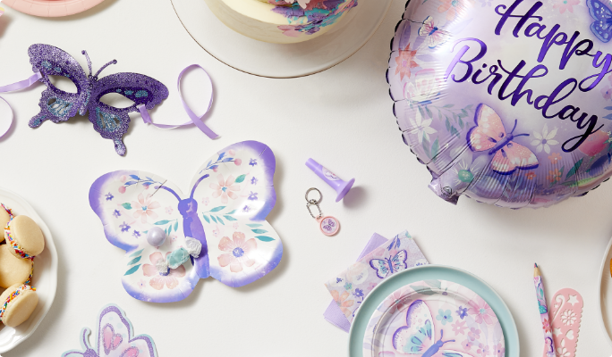 A butterfly shaped plate, a Flutter mylar balloon, desserts and themed favours on a table.