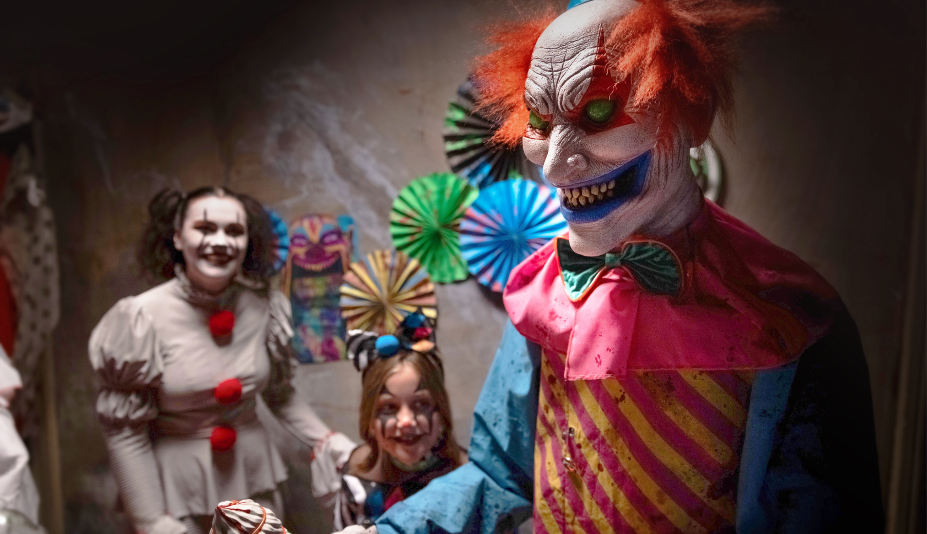 A woman, a girl and a man wearing scary clown costumes in a room decorated with creepy carnival Halloween decor.