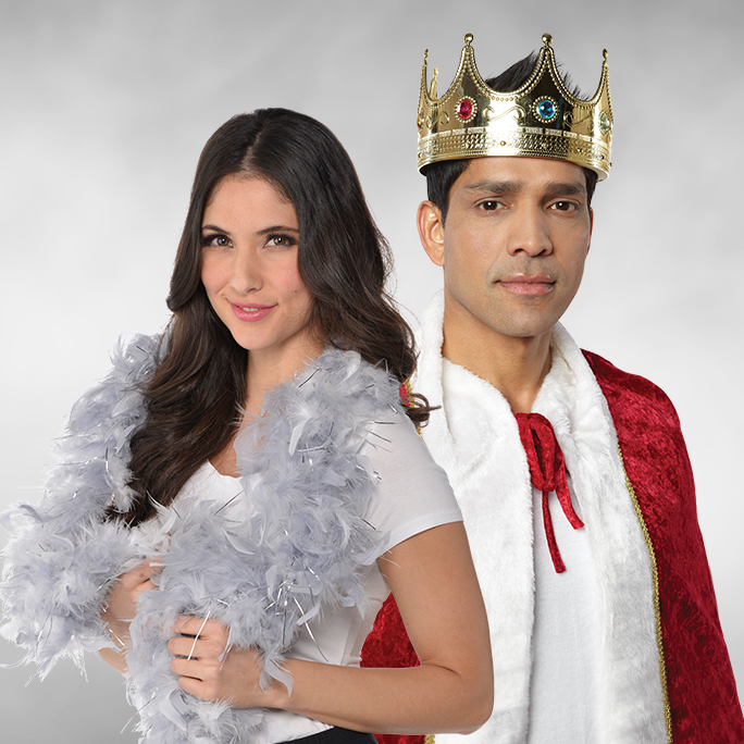 A woman wearing a grey feather boa and a man wearing a jeweled costume crown and cape.