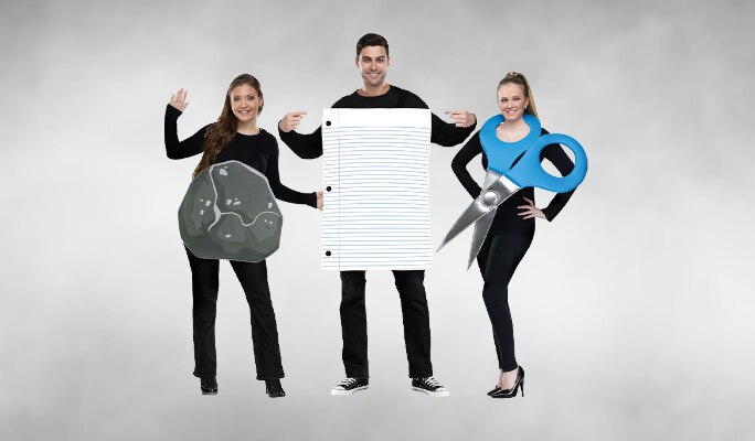 Trois adultes portant un costume de groupe « Roche, papier, ciseaux ».