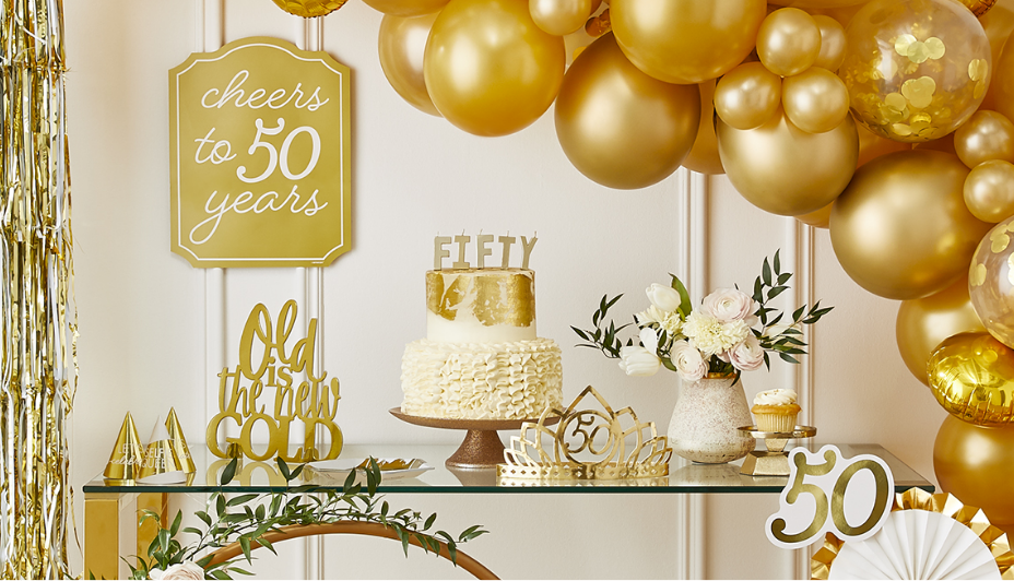 Dessert table with gold balloon arch and 50th birthday party decorations.