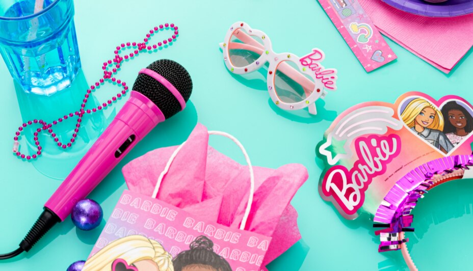 Barbie deluxe sunglasses and other assorted Barbie-themed party favours on a tabletop.