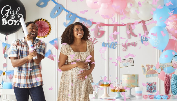Couple celebrating a gender reveal with pink confetti.