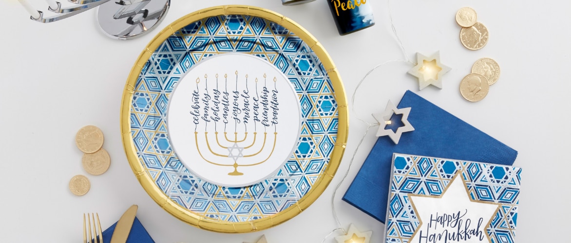 A round blue and gold Hanukkah-themed plate and napkins on a white backdrop.