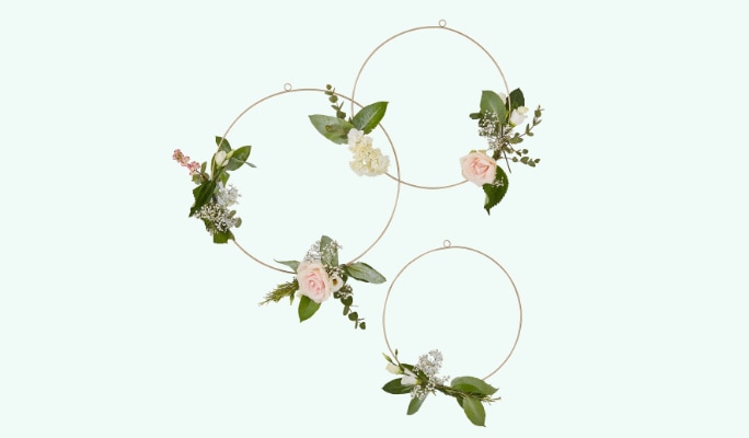Trois anneaux floraux avec fleurs roses et verdure.