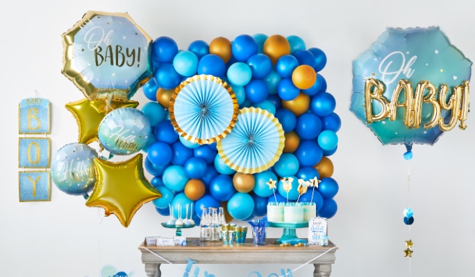 A dessert table surrounded by a blue and gold "Oh baby" balloon arrangement and various "It's a boy" party decorations.