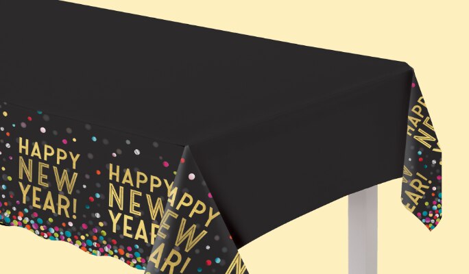A table covered with a black tablecloth with 'Happy New Year!" repeated on it in gold font.