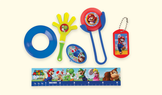 A Super Mario birthday party favour pack, featuring a dog tag keychain, a mini hand clapper, a ruler and a disc shooter. 